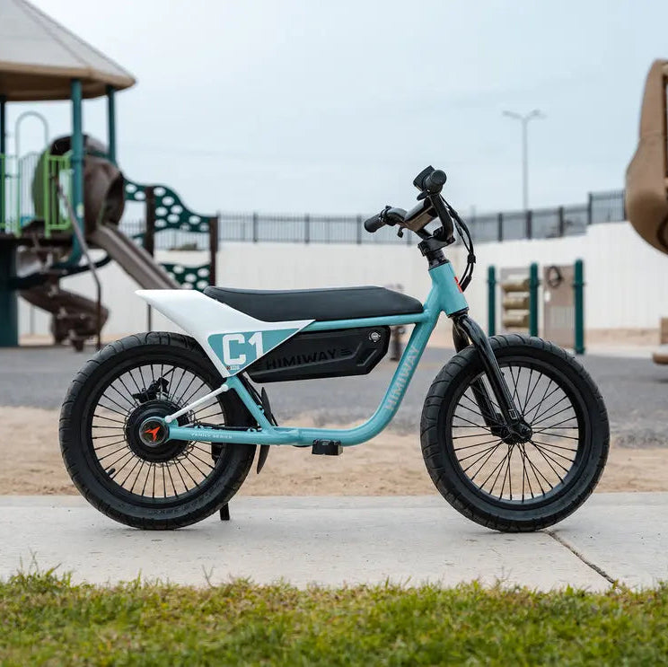 Turquoise electric bike on a sidewalk with playground equipment in the background