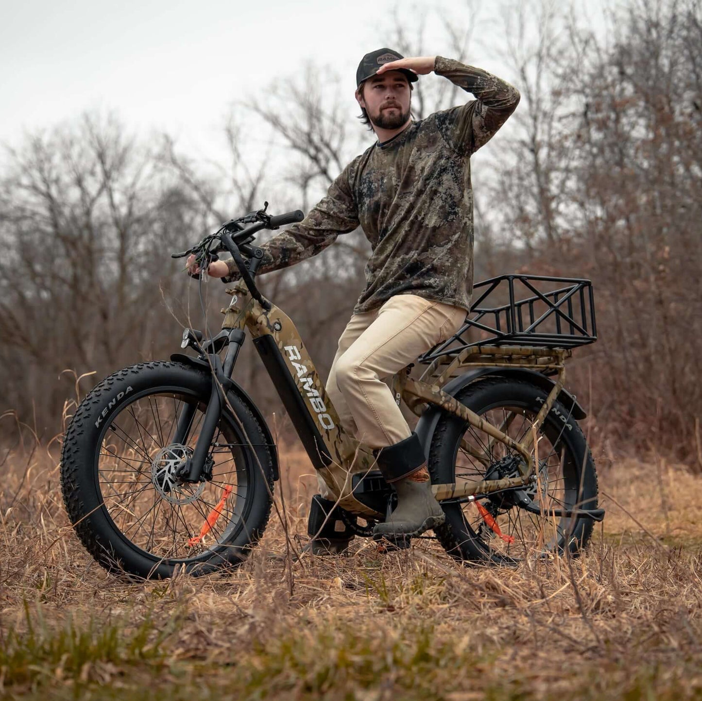 Man sitting on a fat-tire bike in a field with trees in the background