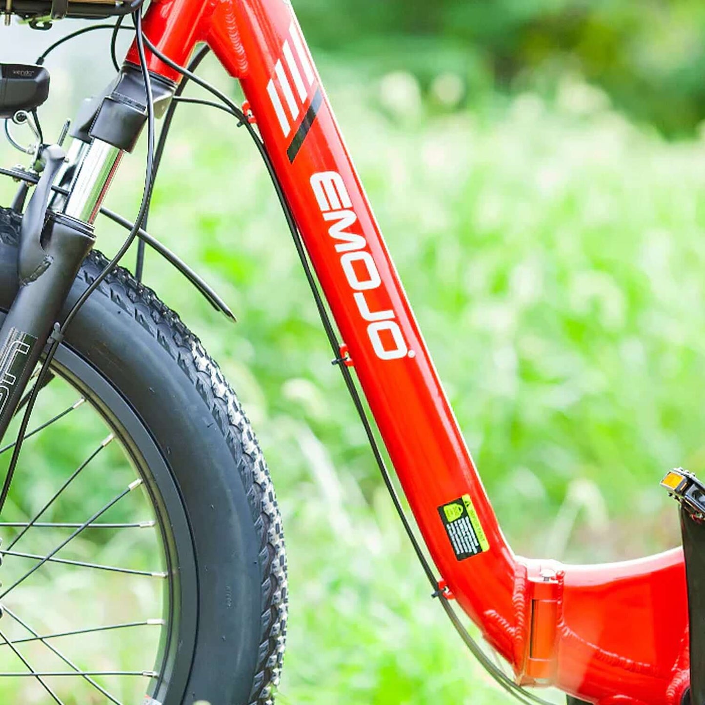 Close-up of the Emojo logo on the frame of a red electric trike, showcasing its durable design and construction.