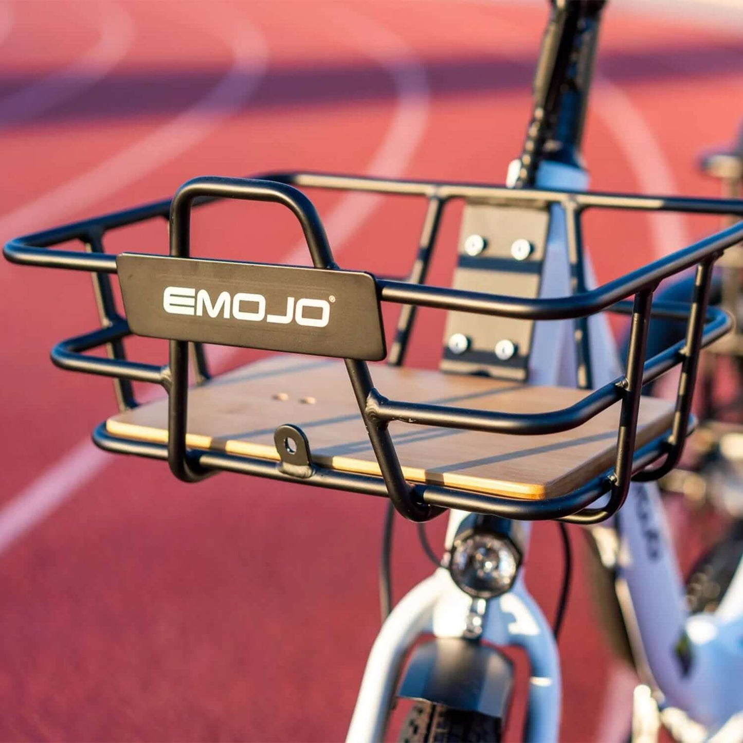 Close-up of Emojo electric trike front basket, showcasing its sturdy design and wooden base on a track background.