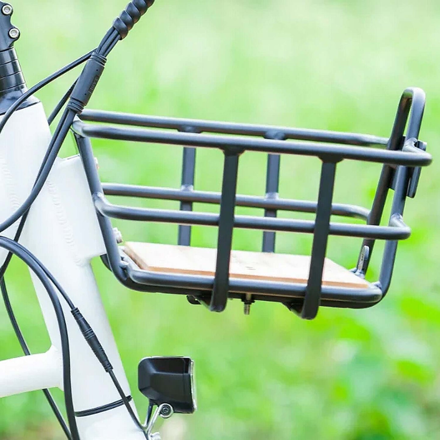 Close-up of a sturdy black bicycle basket with a wooden base attached to an electric trike.