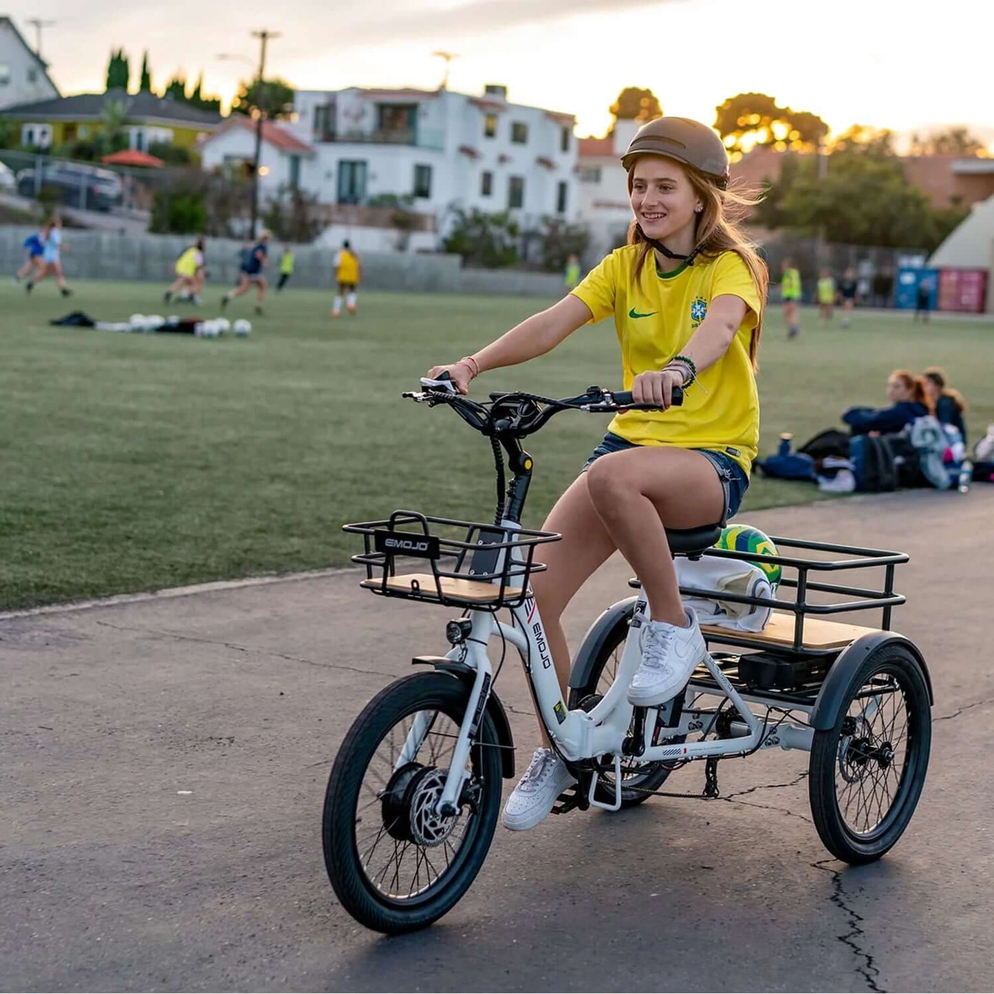 Girl riding Emojo Bison S Step-Thru Electric Trike in a park, wearing a yellow shirt and a helmet.