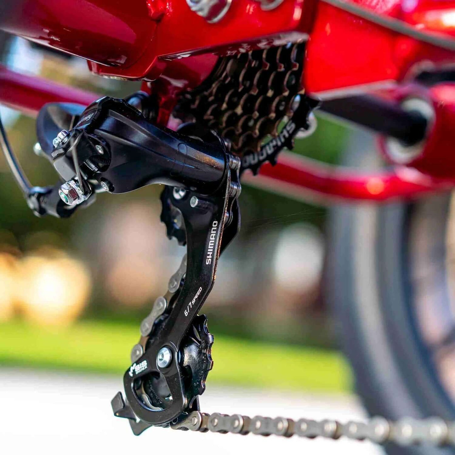 Close-up of Shimano derailleur and chain on a red electric trike, showcasing high-quality bike components.