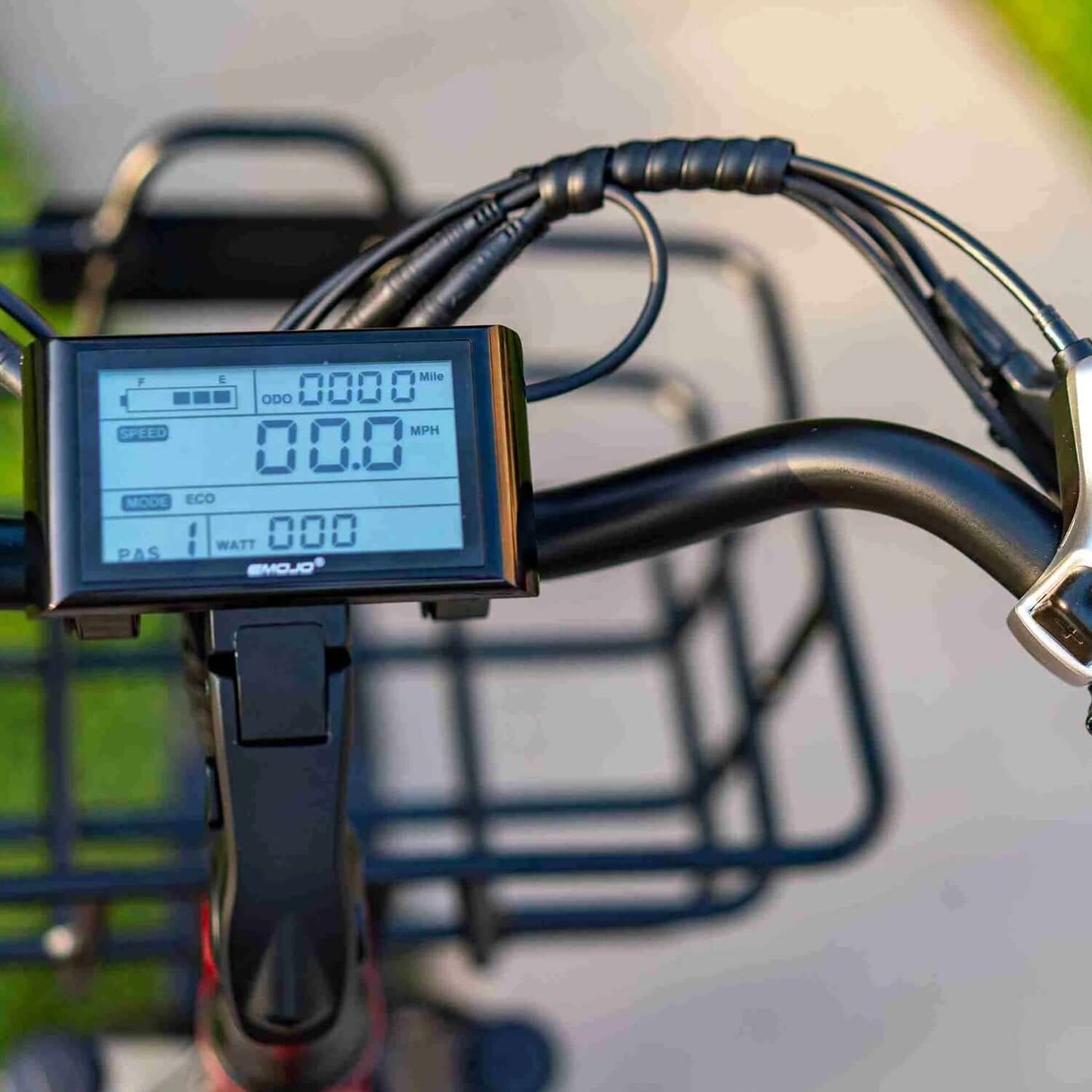 Emojo electric trike display showing speed, distance, and settings on handlebars.
