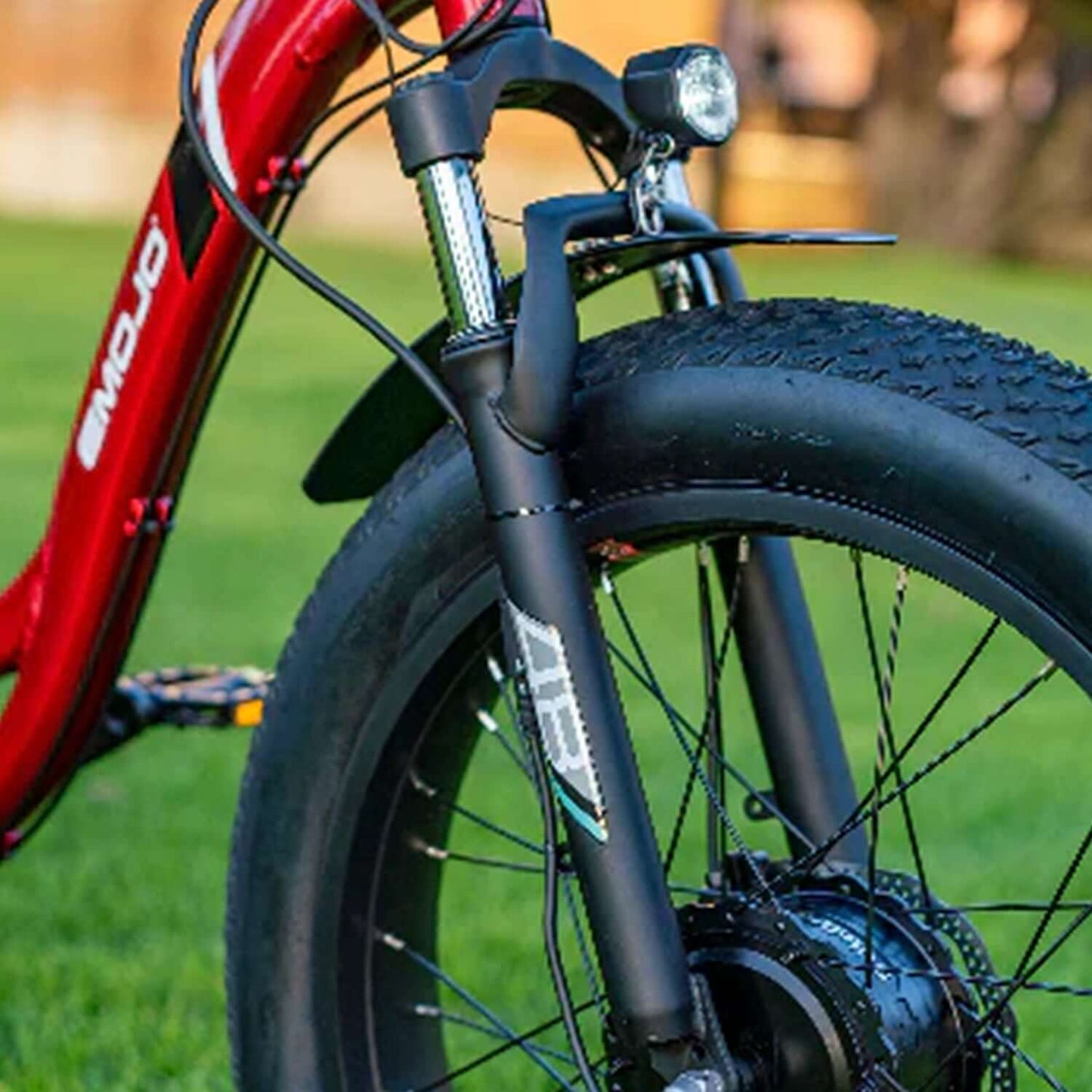 Close-up of Emojo Caddy PRO electric trike front fork and fat tire, showcasing durability and performance.