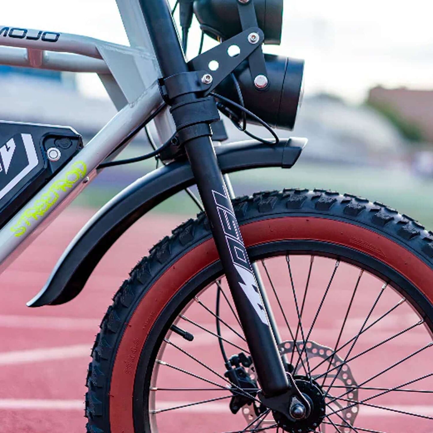 Close-up of the front fork and fat tire of Emojo Streetrod 48V 750W Electric Bike on a running track.