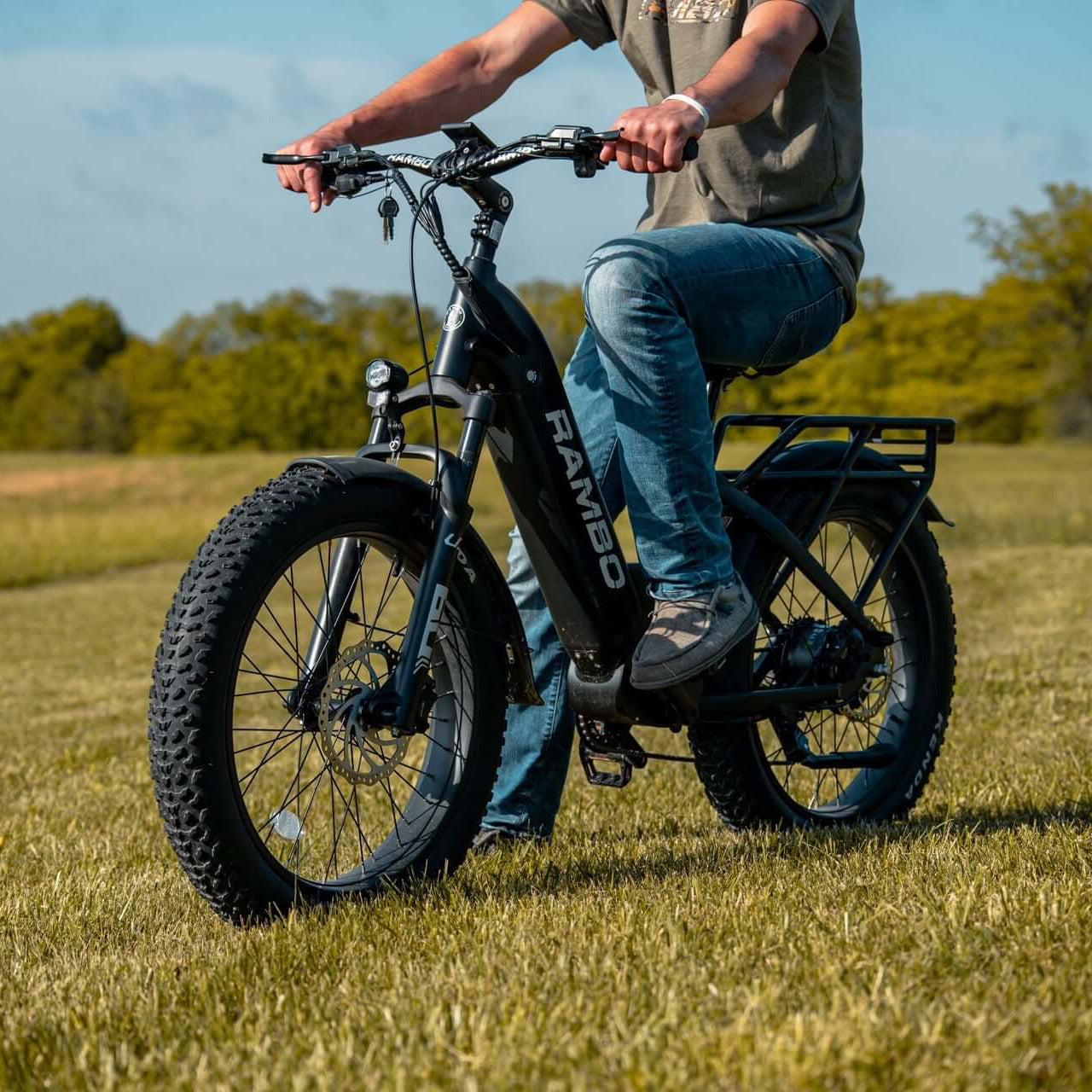 Person riding an electric bike in a grassy field with trees in the background