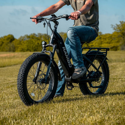 Person riding an electric bike in a grassy field with trees in the background