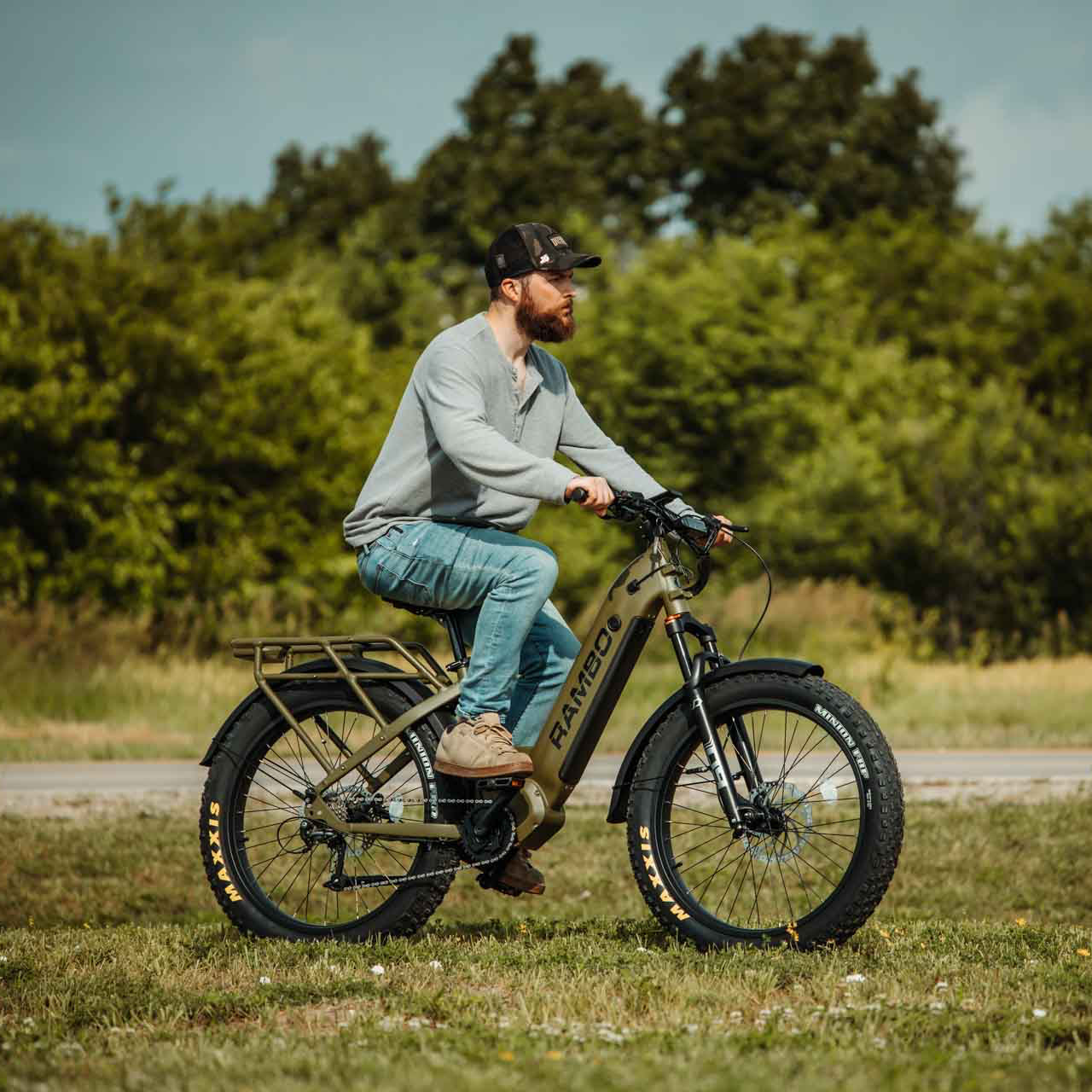 Man riding a large wheel bike in a natural setting with trees and grass.