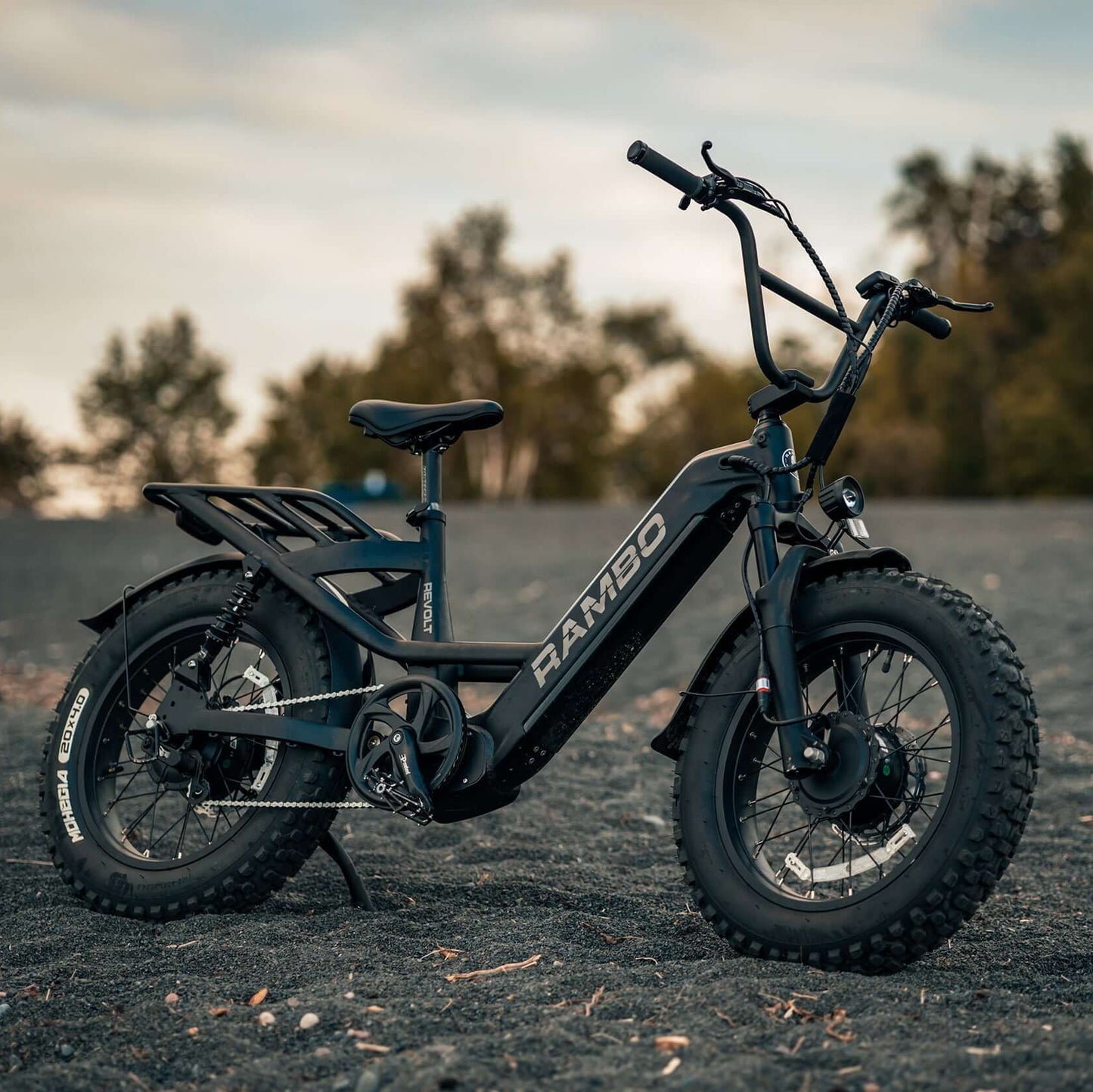 Electric bike with 'RAMBO' branding on a gravel surface with trees in the background
