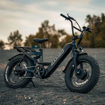 Electric bike with 'RAMBO' branding on a gravel surface with trees in the background
