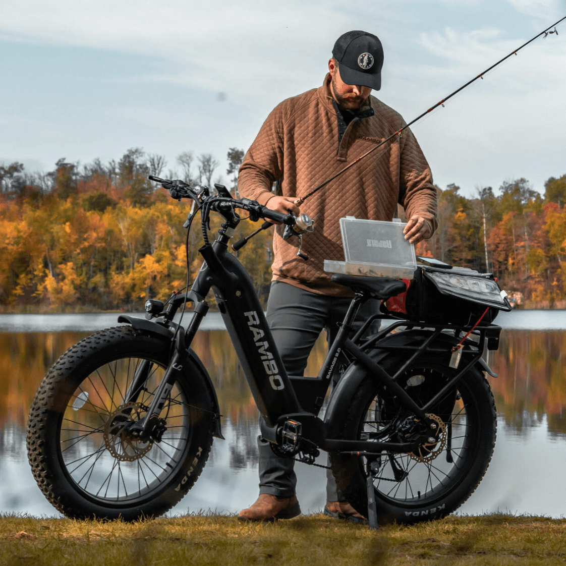 Man with a fishing rod and laptop on an electric bike by a lake