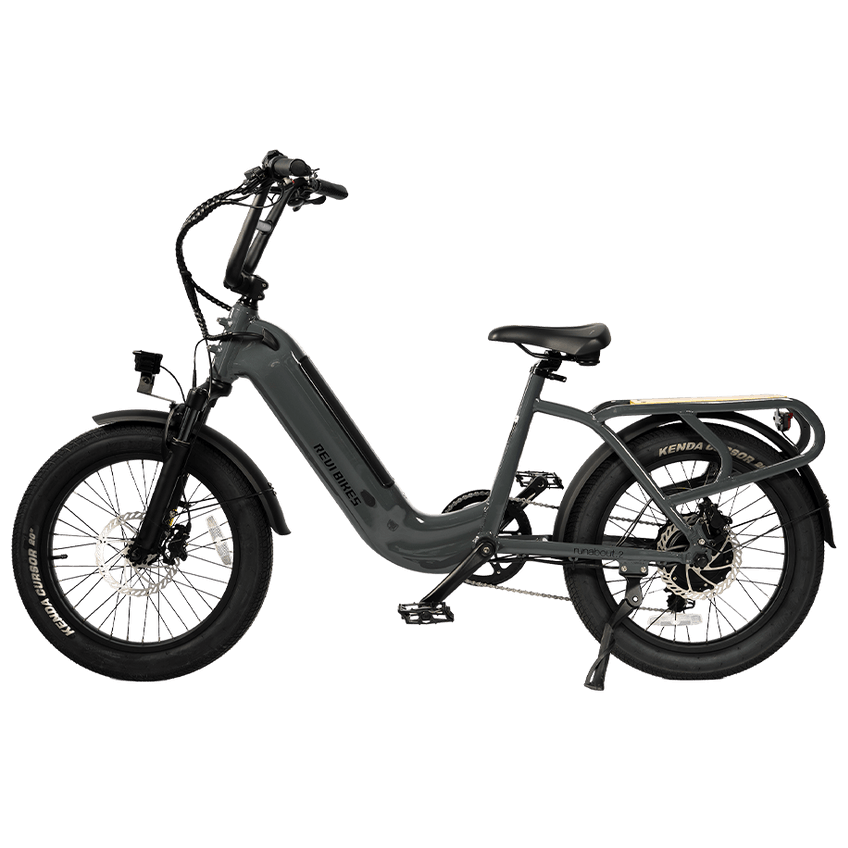 A dark gray step-through electric bicycle with fat tires, rear cargo rack, and disc brakes, shown from a side profile on a solid white background.